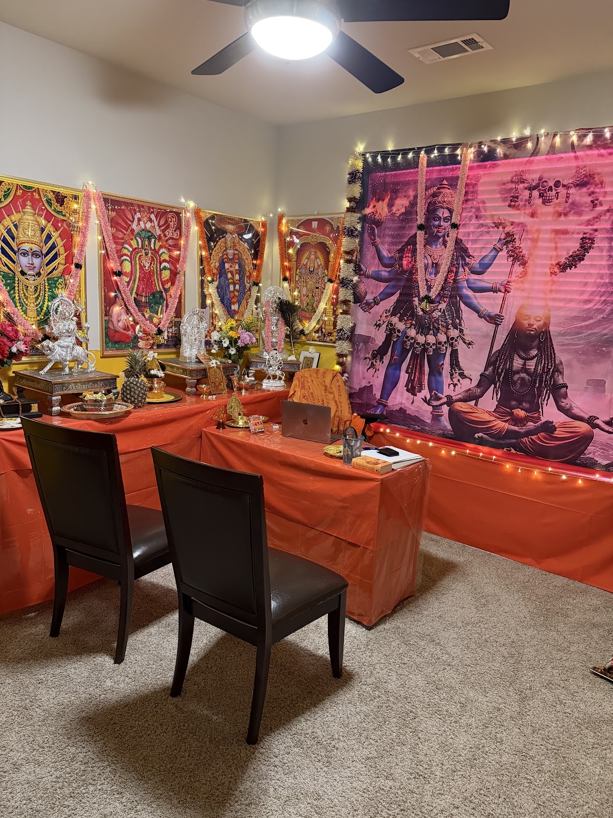 Master Arjun's temple room — saffron altars, garlanded deity art, and silver murtis